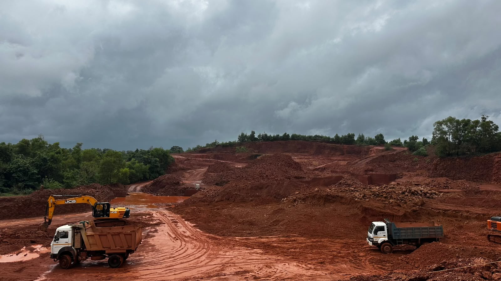 JCB excavator loading trucks at Tierra Milestone Karnataka mining site